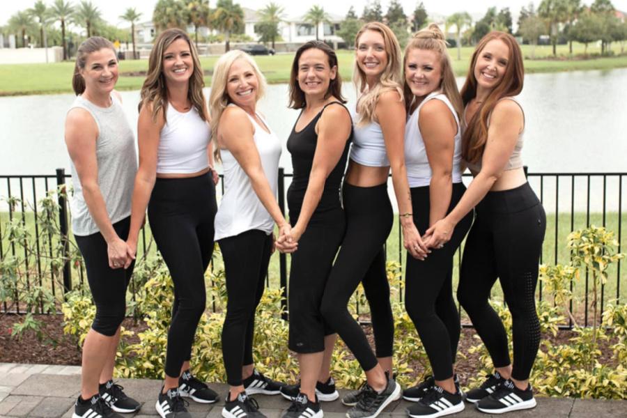 ladies on Mindy's team standing together posing by black fence outside