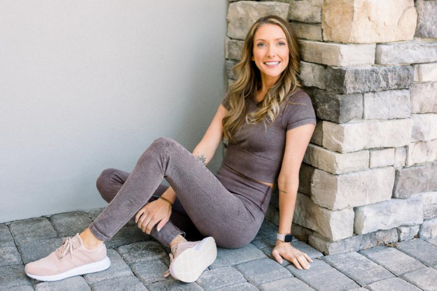 Mindy leaning against brick fireplace with legs crossed